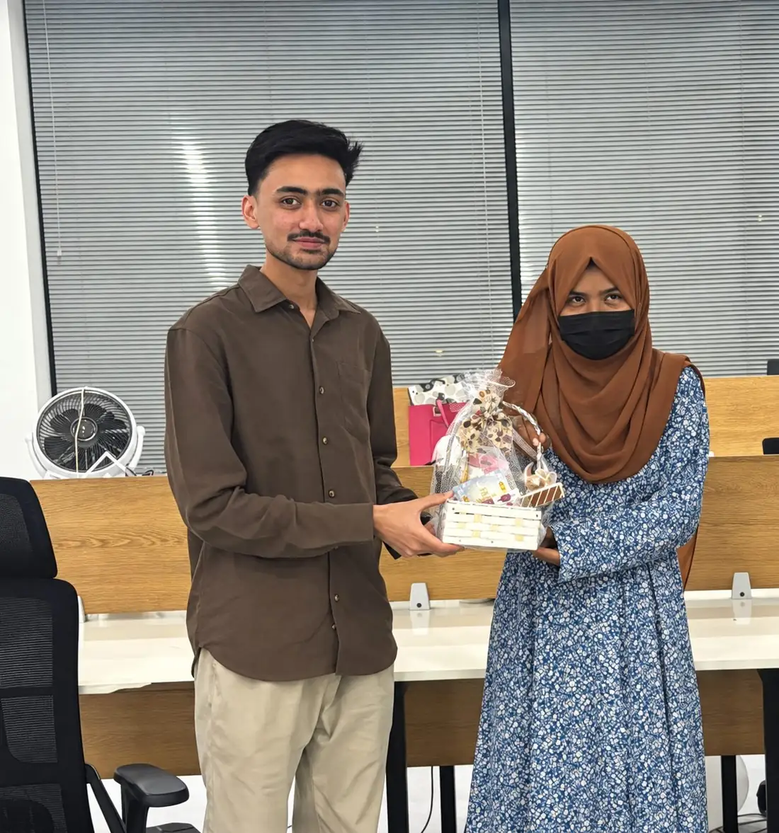 A Topwebs team member receiving an Eid gift basket at the office